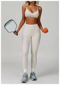 Detail of cream white high-waist yoga set with pickleball paddle in a studio setting