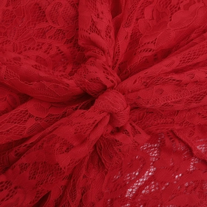 Detailed close-up of red lace fabric with intricate mesh patterns and decorative knots