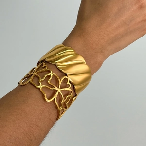 Detail of 18K gold-plated bangles featuring hollow floral patterns and wavy metal designs