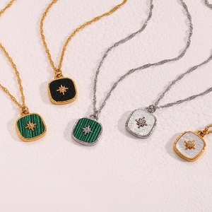 Detailed macro view of square starburst necklaces in black, green, and white enamel