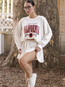 Dettaglio di una felpa bianca oversize con stampa California rossa e gonna a pieghe