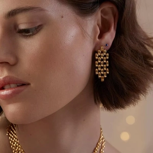 Gros plan de boucles d'oreilles clous dorées tressées avec finition métal brillant