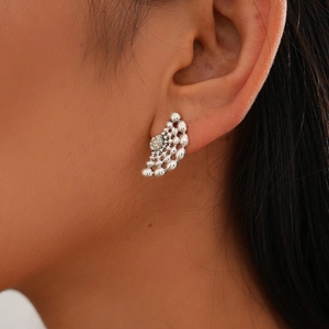 Gros plan de boucles d'oreilles clous argentées avec strass et motif sphérique vintage