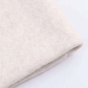 Close-up of soft beige wool coat fabric showing dense texture and thick premium quality