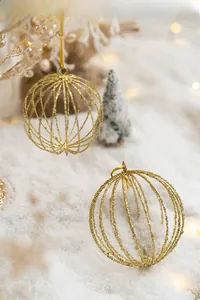 Detail of gold glitter hollow wire Christmas ornaments on a cozy festive snowy background