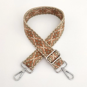 Close-up of geometric jacquard bag strap with silver metal swivel hooks and adjuster