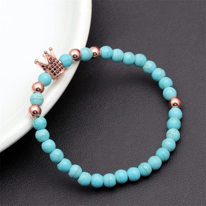 Detail of beaded bracelet with turquoise stones and rose gold crown charm set with black gems