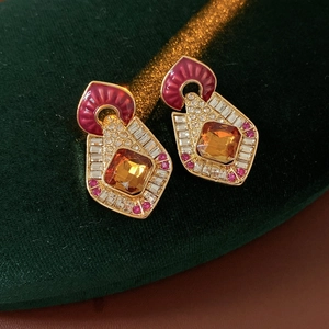 Detailed close-up of vintage gold earrings with amber stone on green velvet