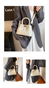 Detail of off-white lychee grain leather handbag with classic metal lock and adjustable strap