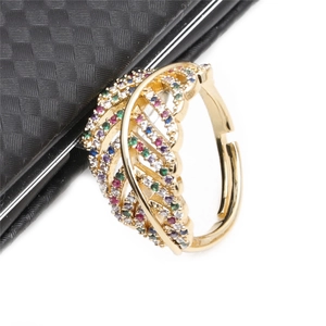 Macro shot of leaf-shaped copper ring with colorful zircons on a dark leather base