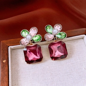 Macro detail of vintage floral earrings with red gems and colorful crystals on fabric