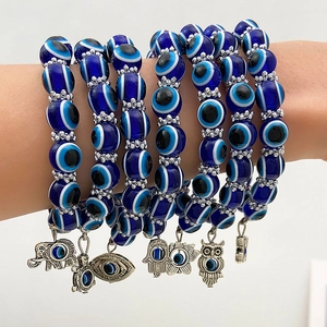 Set van evil eye kralenarmbanden met diverse zilveren gelukshangers om de pols