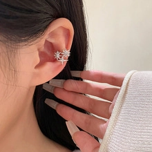 Close-up of sparkling star-shaped silver ear cuff with small crystals on ear