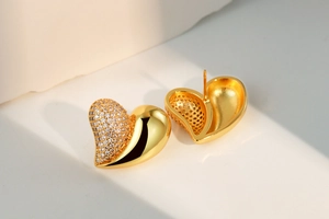 Macro detail of gold heart earrings featuring white pavé zircon and polished finish