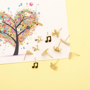 Assorted gold-plated ear studs featuring music notes, planes, and crowns on yellow background