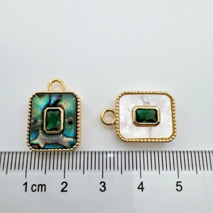 Macro detail of 18K gold plated emerald shell pendants with ruler showing the size
