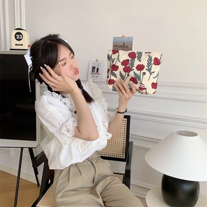 Floral cotton pouch with red poppy print and brand label held by a model