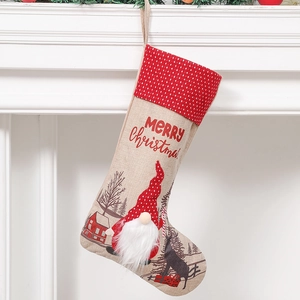 Red Christmas stocking with plush gnome and Merry Christmas text hanging on a white mantle