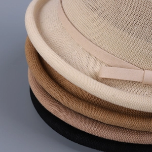 Stack of breathable knitted cloche hats in beige, brown and black with decorative bows