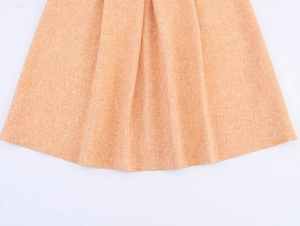 Gros plan détaillé d'une jupe en tweed orange clair avec ourlet plissé et tissu texturé