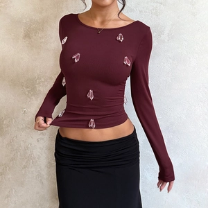 Detail of burgundy ribbed knit long sleeve top featuring dangling crystal rhinestone charms