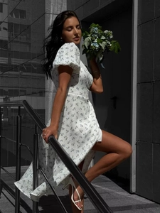 Close-up of cotton floral dress with puff sleeves and side slit on a street model