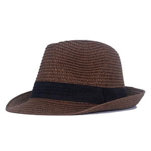 Side view of dark brown straw fedora with black ribbon band on white background
