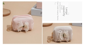 Detail of corduroy coin purse with bow, pearls, and metal keychain in pink and white