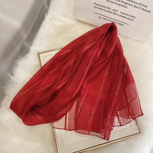 Detail of red silk wool scarf featuring elegant gold metallic stripes on soft fabric
