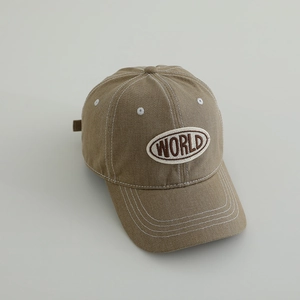 Detailed close-up of light brown canvas baseball cap with embroidered WORLD text and contrast stitching