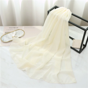 Detail of light beige chiffon scarf draped over a black metal rack and marble surface