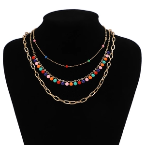 Detail of multi-layered gold chain necklace with colorful beads on a black display