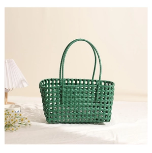 Detail of green hollow-out plastic woven shoulder bag with glossy texture and slim handles