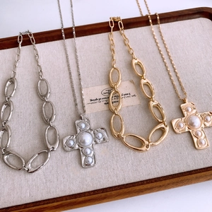 Macro detail of vintage cross pendants with baroque pearls on hammered metal necklaces