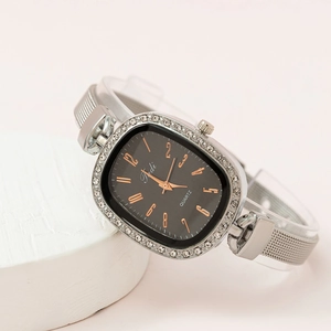 Women's quartz watch with black dial, silver mesh band and crystal bezel on stone display