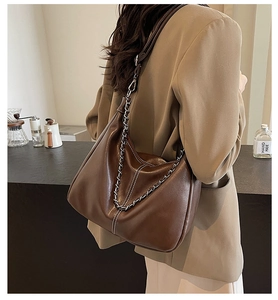 Detail of deep brown leather texture and metal chain strap on a stylish shoulder bag