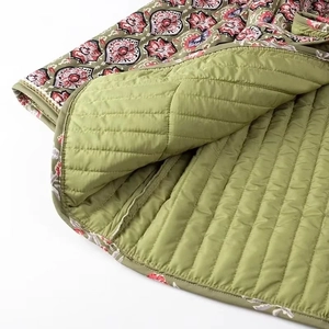 Detailed quilted texture of cotton coat featuring paisley print and green lining