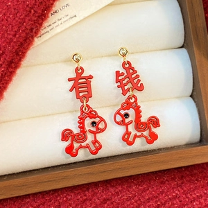 Macro shot of silver needle horse earrings with festive red enamel and gold finish