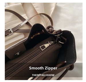 Detailed macro view of the smooth silver metal zipper and fabric lining on a dark brown tote