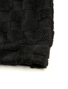 Gros plan sur le sweat-shirt en polaire noire avec texture damier en relief et douceur