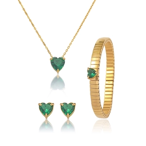 Close-up of gold jewelry set featuring emerald heart-shaped stones and polished finish