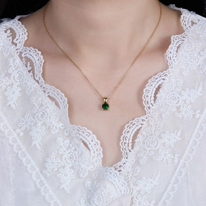 Detail of 925 silver gold necklace featuring a round green gemstone pendant on lace
