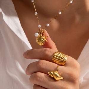 Detailed shot of gold necklace and rings with pearl, starfish and seashell charms