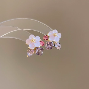 Macro detail of floral pearl earrings with pink and lavender crystals on gold base