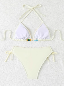 Detailed flat lay of beige bikini set featuring colorful crochet flower embroidery