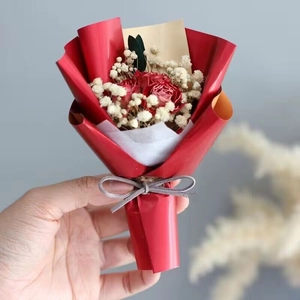 Close-up of mini red dried rose bouquet with baby's breath and a grey velvet bow