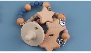 Detailed view of silicone pacifier with beech wood clip and colorful beads on blue surface