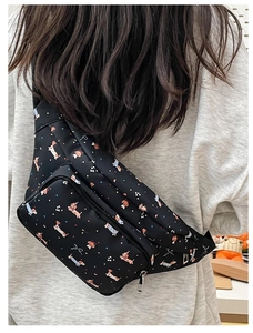 Close-up of black crossbody bag featuring cartoon dachshund patterns and silver zippers