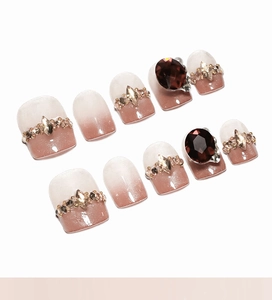 Detail of coffee cat-eye gradient press-on nails with rhinestones and gems in a set