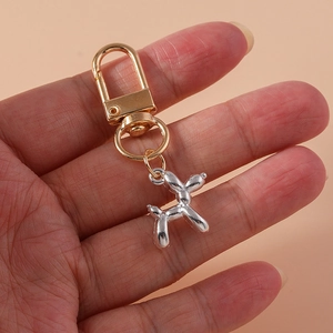 Detailed macro view of a silver metallic balloon dog pendant with golden lobster clasp
